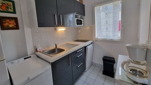 Una cocina compacta equipada con microondas, pileta y ventana con vidrio esmerilado.