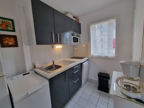 A compact kitchen with a microwave, sink, and a window with frosted glass. - House near the beach, pets welcome - 4 guests (Sarzeau)
