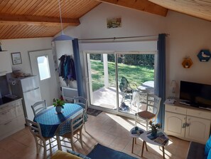 Ein gemütliches Zimmer mit Esstisch, Stühlen, Fernseher und Küchenzeile.