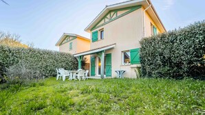 A two-story house with a patio, a table, and chairs. - Charming duplex near beach - 5 guests (Bias)
