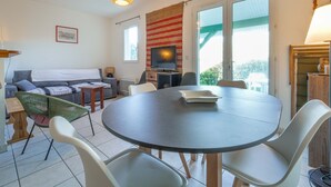A living room with a round table, chairs, a sofa, a television, and a window with a view. - Charming duplex near beach - 5 guests (Bias)