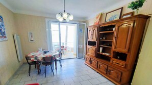 A dining area with a table, chairs, and a wooden cabinet. - Lovely apartment with panoramic view - 6 guests (Canet-en-Roussillon)