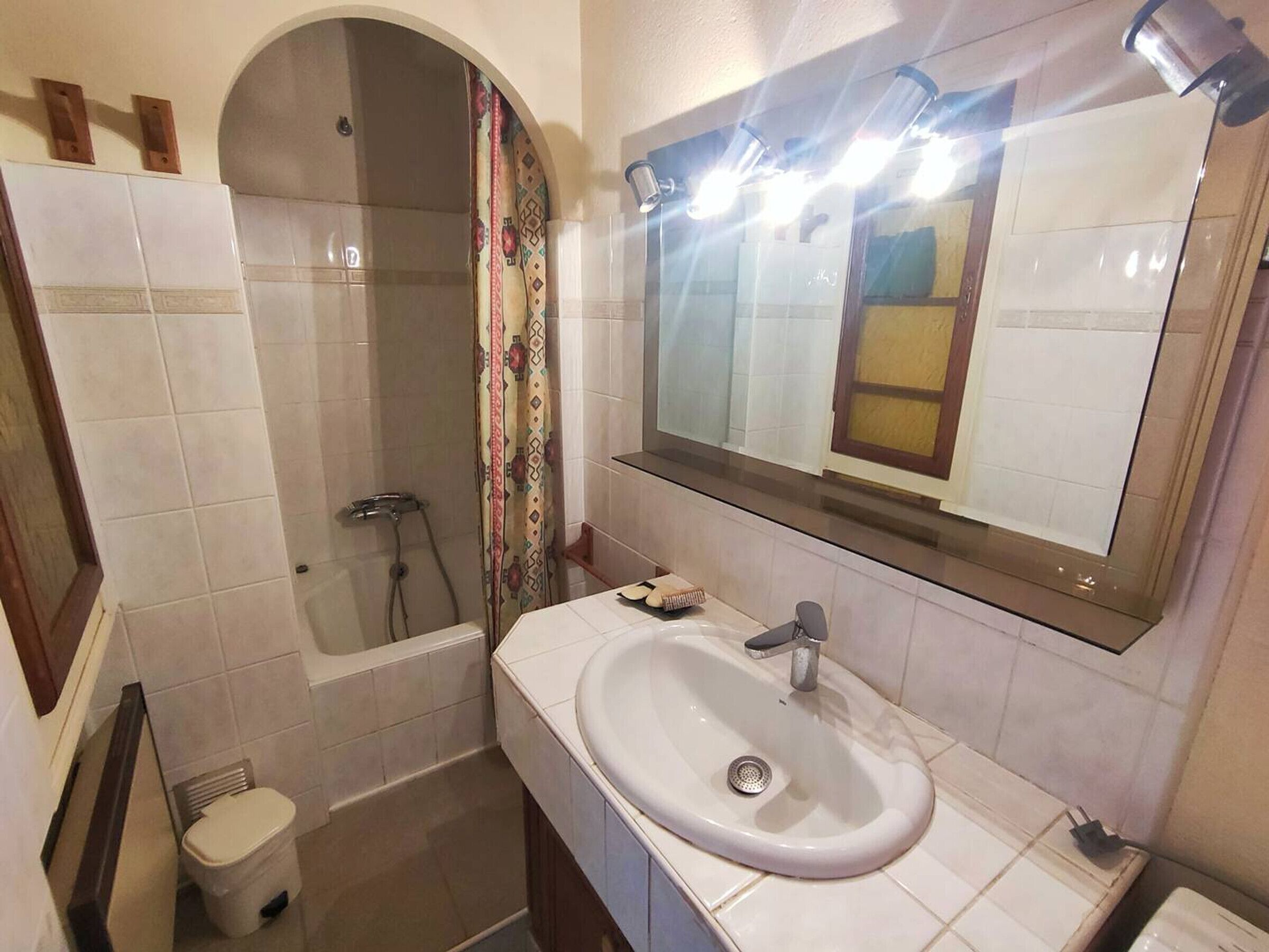 A bathroom with a shower, toilet, sink, and mirror.