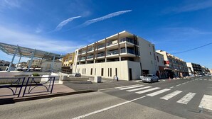 Un edificio de varios pisos con balcones, un paso de peatones y un cielo despejado.