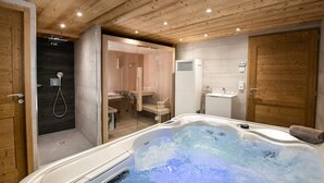 Ein Wellnessraum mit Whirlpool, Dusche und Sauna.