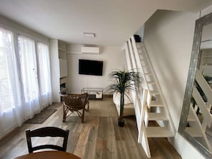 Ein modernes Wohnzimmer mit Treppe, Flachbildfernseher und einer Topfpflanze.