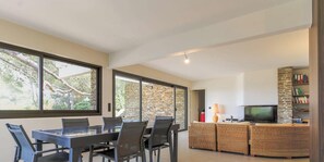 Ein modernes Wohnzimmer mit Essbereich, Steinwand und Fernseher.