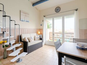 Ein Zimmer mit einer Couch, einem Esstisch, einer Uhr und Blick durch eine Glastür.