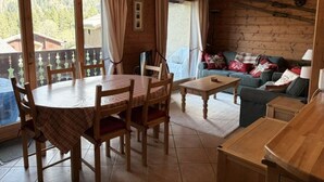 Puisesti sisustettu tila, jossa on ruokapöytä, tuoleja, sohva ja pieni pöytä.