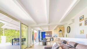 Ein modernes Interieur mit Essbereich, Küche und einem Balkon mit Blick auf Grünflächen.