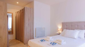 Ein Hotelzimmer mit einem Bett, einem Nachttisch, einer Wandheizung und einer Holztür.