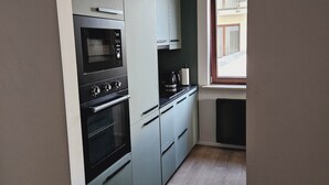 A modern kitchen with a built-in oven, microwave, and a window providing natural light. - Garbary Residence II Old Town (Poznań)