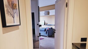 A hallway leading to a living area with a sofa, a small table, and a framed picture on the wall. - Garbary Residence II Old Town (Poznań)