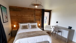 Un dormitorio moderno con cabecera de madera, cama con ropa blanca, un escritorio y una silla.