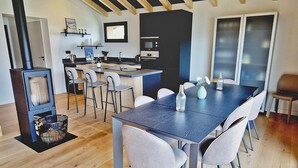 Una cocina moderna con una isla central, asientos tipo barra y un comedor con una mesa larga.