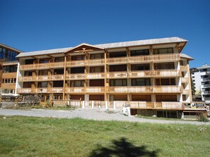 A multi-story hotel with wooden balconies and a restaurant at the ground level. - Apartment on slopes, 8 guests (Pra-Loup)