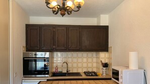 Uma cozinha com armários de madeira escura, forno de aço inoxidável, micro-ondas e painel de azulejos.