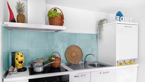 Una cucina con piano di lavoro bianco, fornello, lavello e mobiletto bianco.