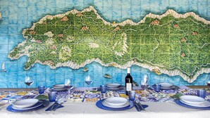 Un tavolo imbandito con piatti, bicchieri e una bottiglia, con un grande murale raffigurante una mappa sullo sfondo.