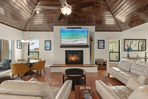 A living room with a fireplace, a ceiling fan, and a television mounted above it. - Waterfront Home w Private Dock Hot Tub Fire Pit (Miramar Beach)