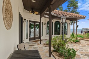 A covered patio with stone flooring, a ceiling fan, and a sign reading 'CASA DE PER.' - Waterfront Home w Private Dock Hot Tub Fire Pit (Miramar Beach)