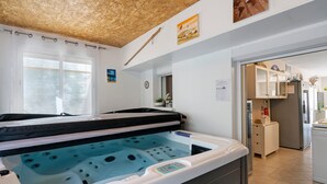 Une salle de spa équipée d’un bain à remous, avec un plafond en bois et une vue sur la cuisine.