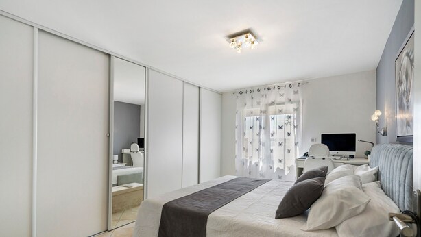 Une chambre à coucher moderne, équipée d’un lit, d’un bureau et d’une télévision.