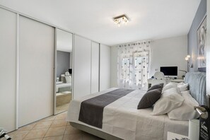 Une chambre à coucher moderne, équipée d’un lit, d’un bureau et d’une télévision.