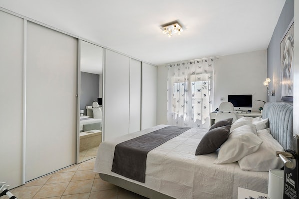 A modern bedroom with a bed, a desk, and a television.