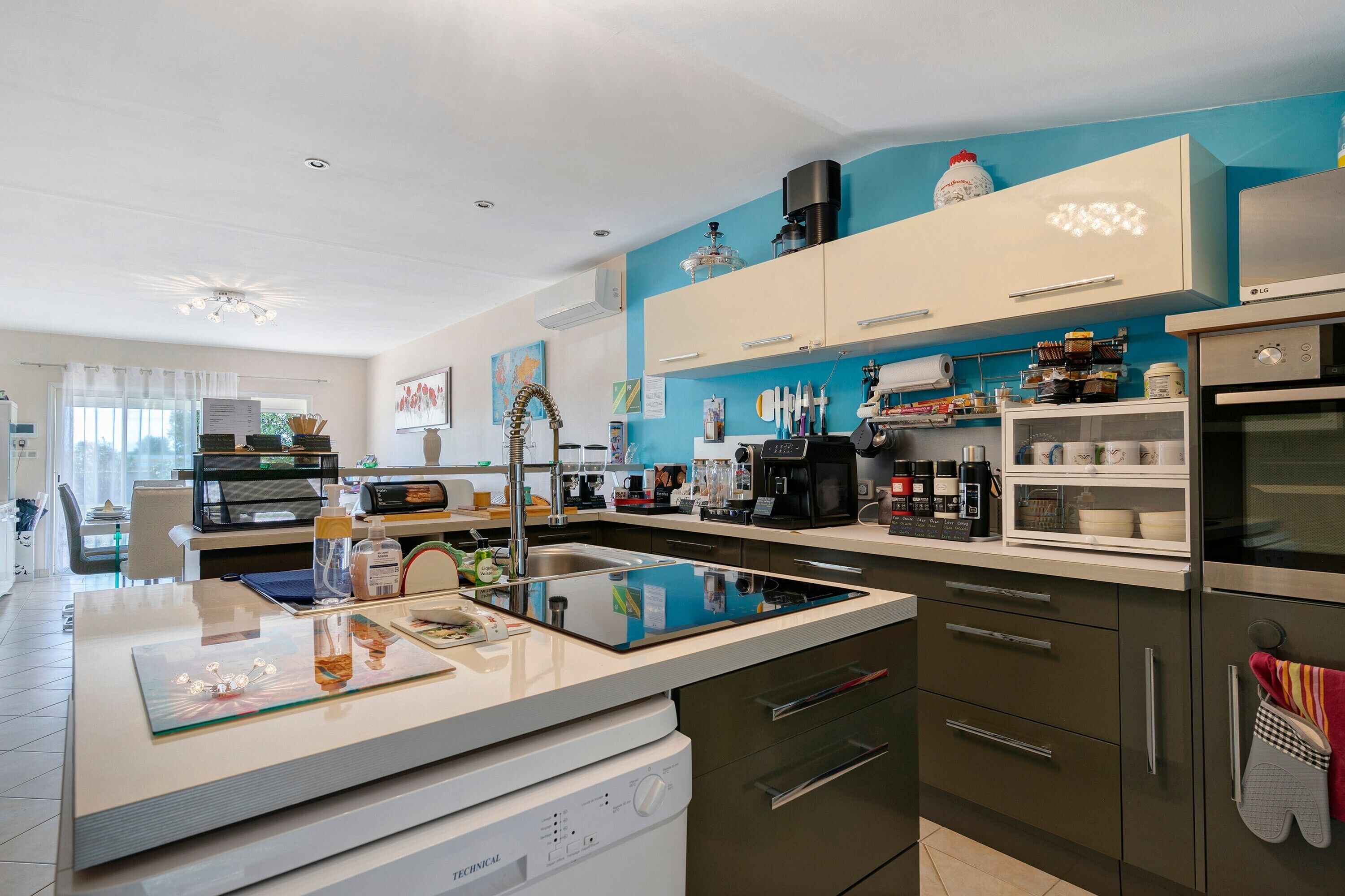 Une cuisine moderne dotée d’un îlot central, d’appareils électroménagers en acier inoxydable et d’un mur d’accent bleu.