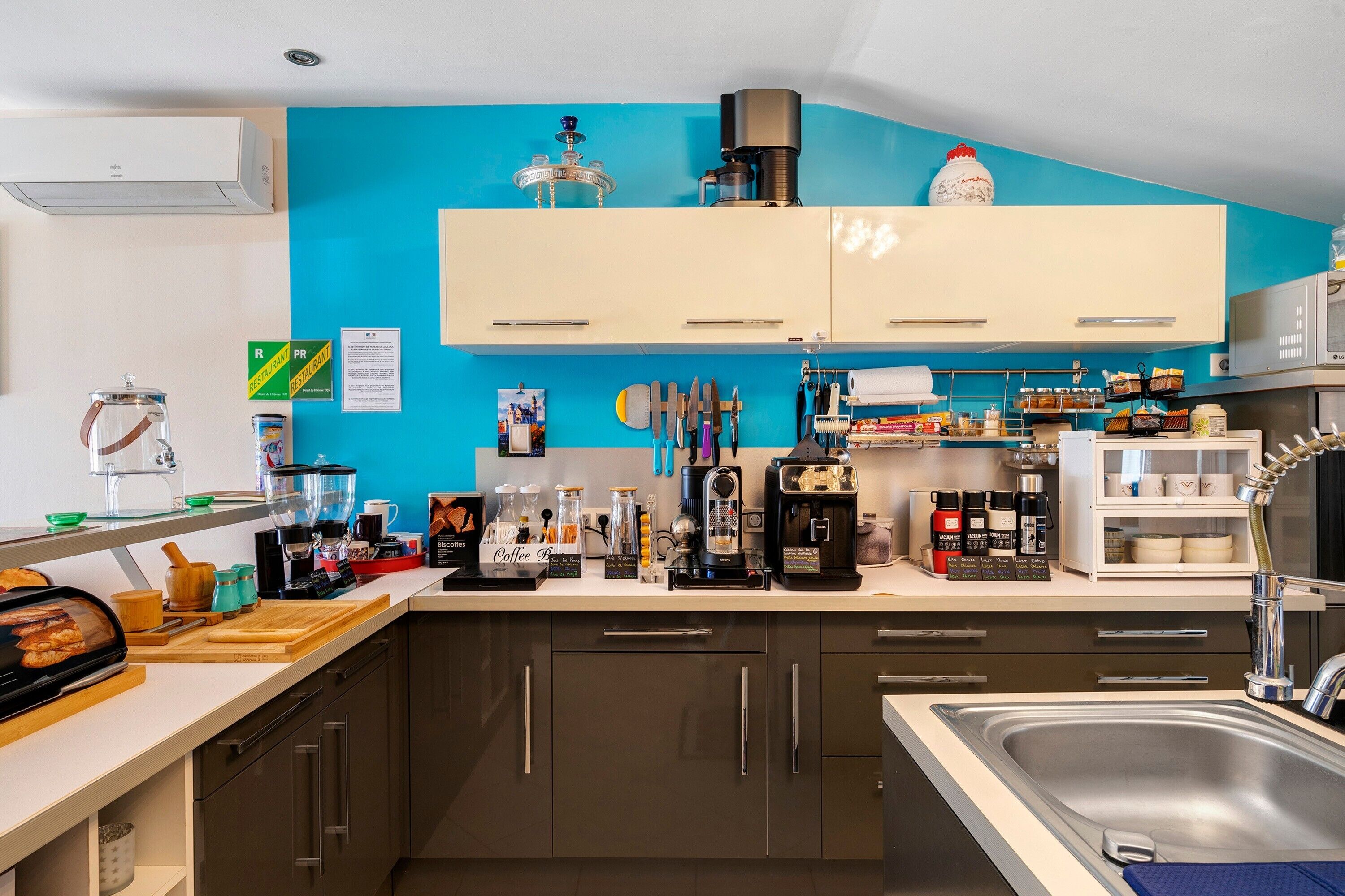 Una cocina moderna con una pared azul de acento, electrodomésticos de acero inoxidable y una variedad de equipos para preparar café.