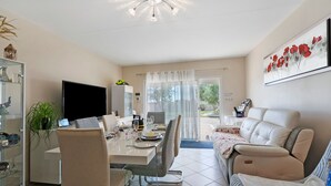 Un salon moderne comprenant un coin repas, un téléviseur à écran plat, un canapé et une table à manger pour quatre personnes.