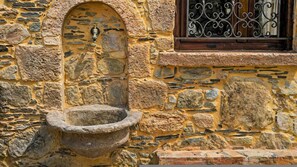 A stone wall with a stone sink and a window with decorative iron bars. - Harmony House- Sea View Cretan Escape With Jacuzzi (Kissamos)