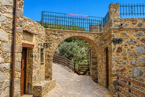 A stone pathway leading through an archway, flanked by stone buildings with a metal railing on top. - Harmony House- Sea View Cretan Escape With Jacuzzi (Kissamos)