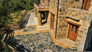 A stone building with a balcony, a wooden door, and a stone-tiled patio. - Harmony House- Sea View Cretan Escape With Jacuzzi (Kissamos)