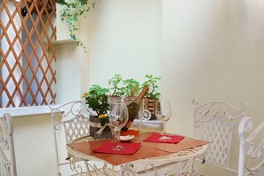 A round table with two wine glasses and red napkins, surrounded by white metal chairs. - Airoldi Palace Apartment: Comfort Between Sea and City (Chioggia)
