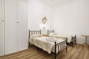 A bedroom with two beds, a wardrobe, a mirror, and a bedside table. - Airoldi Palace Apartment: Comfort Between Sea and City (Chioggia)