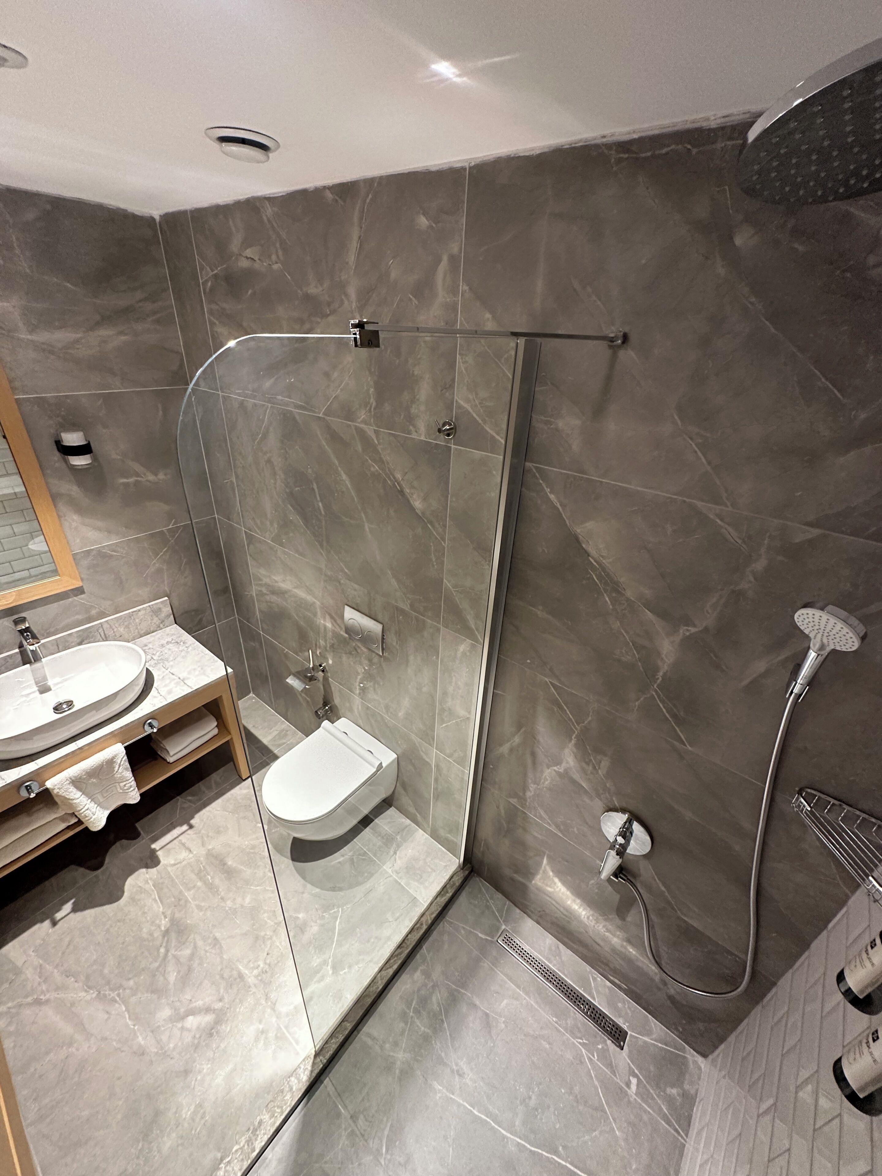 Un baño moderno con ducha de vidrio, lavamanos y retrete.