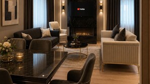 Una sala de estar moderna con chimenea, televisor de pantalla plana y comedor con mesa de vidrio.