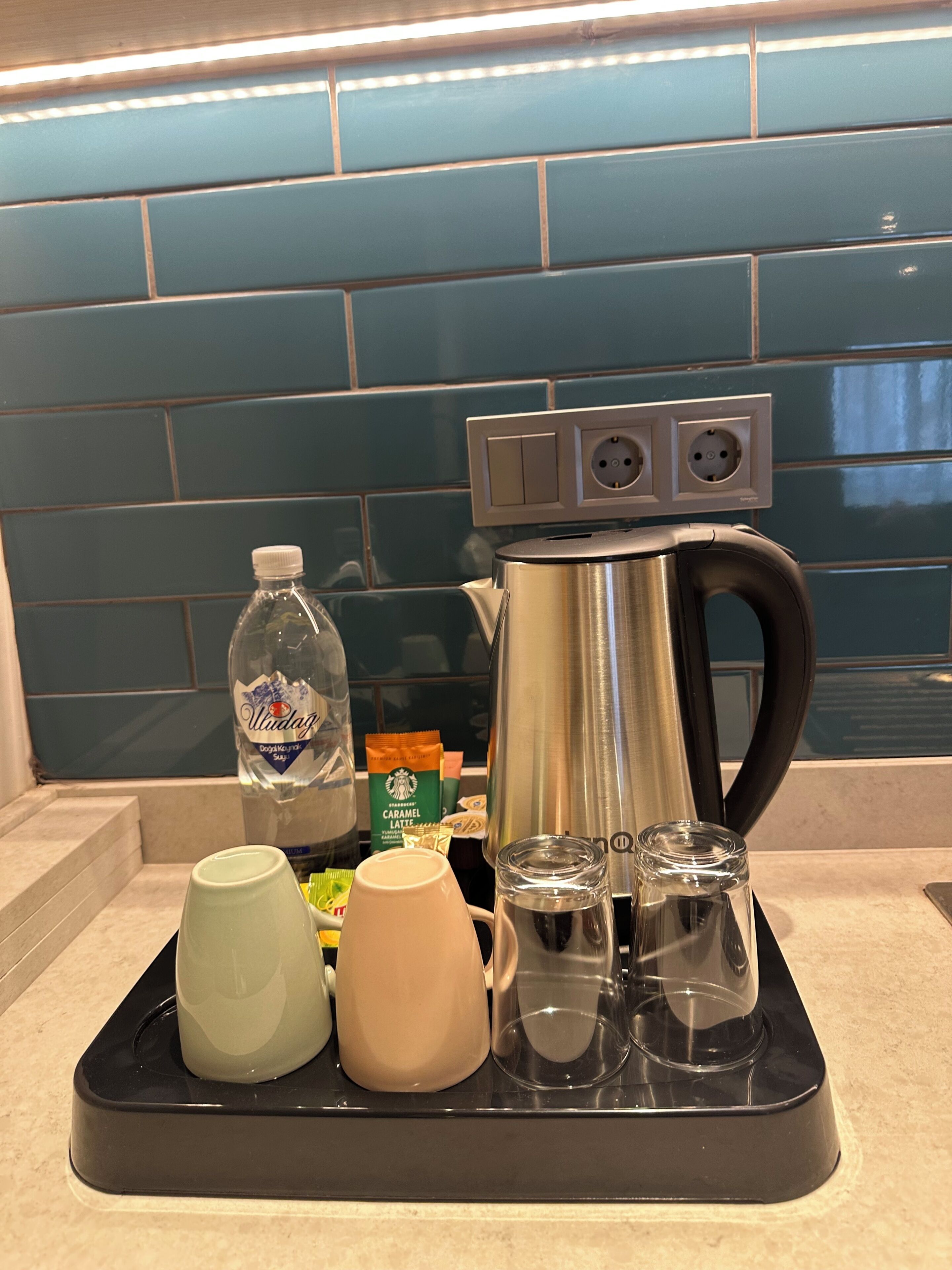 A kitchen counter with a coffee maker, a water bottle, a mug, a pitcher, and a glass carafe.