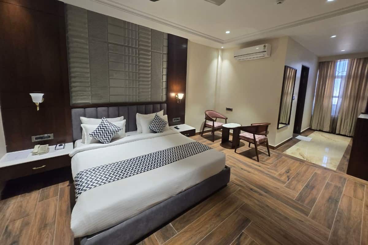 Habitación de hotel con una cama grande, mesitas de noche, un escritorio, sillas, un equipo de aire acondicionado y un ventilador de techo.