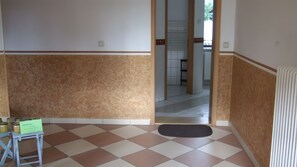 A room with a tiled floor, a small table with jars, and a door leading to another room. - Apartment 'Für 3 Personen 63 M²' (Rötha)
