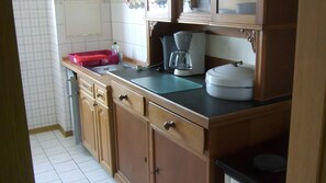 A kitchen with wooden cabinets, a countertop, a coffee maker, and a red container. - Apartment 'Für 3 Personen 50 M²' with Shared Garden (Rötha)