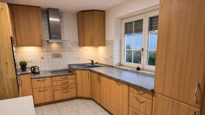 A kitchen with wooden cabinets, a stainless steel range hood, a window with blinds, and a tiled floor. - Apartment 'Control Suites Og Rechts' with Private Terrace and Wi-Fi (Urbar)