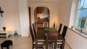 A dining area with a long table, chairs, a potted plant, a small table with a plant, and a window with a view. - Apartment 'Control Suites Og Rechts' with Private Terrace and Wi-Fi (Urbar)