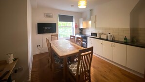 Una cocina compacta con una mesa, sillas, un televisor y un ventanal.