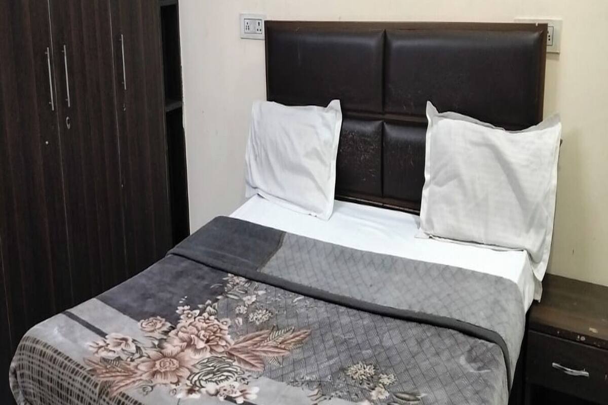 A bed with a floral bedspread, a dark headboard, and white pillows.