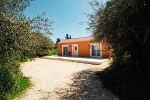 Un bâtiment d’un seul étage, doté d’un toit en tuiles, d’une allée en gravier et d’un petit espace patio.