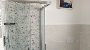 A bathroom with a glass-enclosed shower, a bidet, and a toilet.