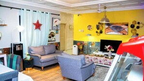 Sala de estar com sofá, televisão e uma parede vermelha de destaque.